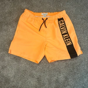 Calvin Klein badshorts  - Säljer nu mina snygga Calvin Klein badshorts. Riktig snygg färg och i bra skick. Storleken är 12-14 år så borde passa runt 140-150 cm. Hör av er vid frågor och funderingar.
