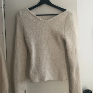 Tröja  - En vit tröja som sitter figursydd tight och har en vringning fram och baktill men de går inte så djupt ner 