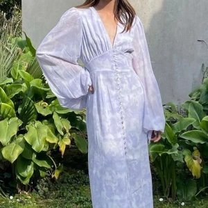 Adoore Positano klänning  - Klänning från Adoore Stora långa ärmar med resår i ärmslut Knappar framtill Dold dragkedja i rygg Slit framtill  Fodrad  