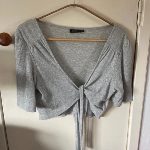 Grå bolero med knytning  - Söt bolero med lite glitter i (se bild 2) Stl M från Lindex  Mjukt material 