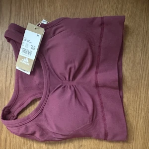 Sport top Adidas M - En sömlös bh från Adidasmed lätt stöd som framhäver dina former. Kompressionspassform Sömlöst material i 86 % återvunnen nylon, 14 % elastan Skulpterad känsla Uttagbara inlägg