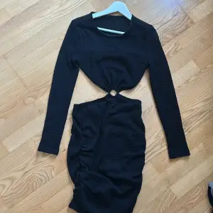 En helt oanvänd kort svart klänning med öppning i ryggen som går ihop i magen. Super fin, enkel och elegant.