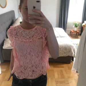 Rosa spets topp - En rosa kortärmad tröja/linne i spets, med söta broderade små detaljer. Sparsamt använd.  Står storlek M men är snarare S i passformen.