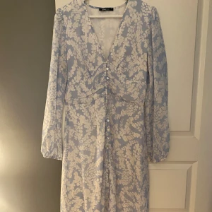 Klänning  - Fantastisk ljusblå klänning ifrån Gina Tricot med blommor och knappar fram. Liten i storleken. 