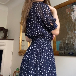 Klänning från Hunkydory - Magisk klänning som passar allt från vardag till fest! Klänningen är i ett svart, flowy material som pryds av ett fint mönster i vitt. Använd 2-3 gånger och är därför i ett mycket bra skick. Extra knapp medföljer. Slutsåld modell. Nypris runt 2500 kr