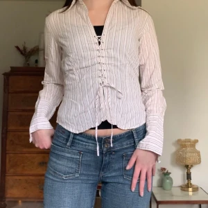 Randig skjorta - Vit skjorta med beiga ränder och unik snörning på flera ställen, vintage Vero Moda! ✨