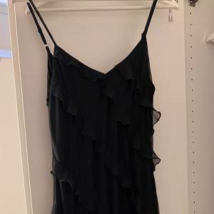 Säljer denna underbara volang klänning i svart. Denna klänning är helt oanvänd. Denna klänning har även en slits vid sidan