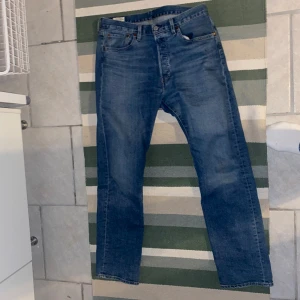 Levis 501 Blåa - Säljer mina blåa Levis 501 för jag inte använder dom längre. Byxorna är i toppskick. Byxorna är strax över 40cm i midjan och strax över 100cm i längden. Kan även tänka mig att gå ner lite i pris vid snabb affär. 