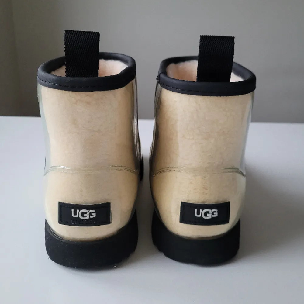 Säljer näst intill nya, Clear Mini, låga, vattentäta boots från UGG.   Fodrade med fårskinn. Ovandelen genomskinlig plast.  Vattentäta, varma boots!  Storlek 36 (mer som 37)  Använda endast 3 gånger pga lite för stora i storleken!. Skor.