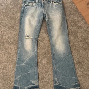 Low waist jeans - Ett par as snygga low waist jeans med ett hål på höger ben. As snygga detaljer men säljer för att de är för små för mig! Innerbenslängd 75 och midjemått 38 rakt över! 