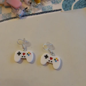 Örhängen med hänge av en handkontroll . - Tuffa örhängen med hänge av en handkontroll .Helt nya och oanvända .