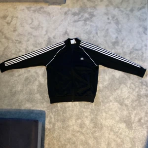 Adidas Zip Up - Adidas Zip up i Toppen Kvalitet ! Som ny fortfarande. Använt 2-3 gånger. Storlek XL herr. Färg: svart.  Har flera Lappar som visar att den är original men hade inte plats med dom pg av att det är Max 5 bilder så skriv till mej isåfall för bilderna 😊