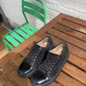 Lanvins, svart med glansig tåbox - Snygga svarta lanvins med glansig tåbox. Aningen slitna i hälen men inget som märks av vid användning av skorna. Prutning uppskattas ej !