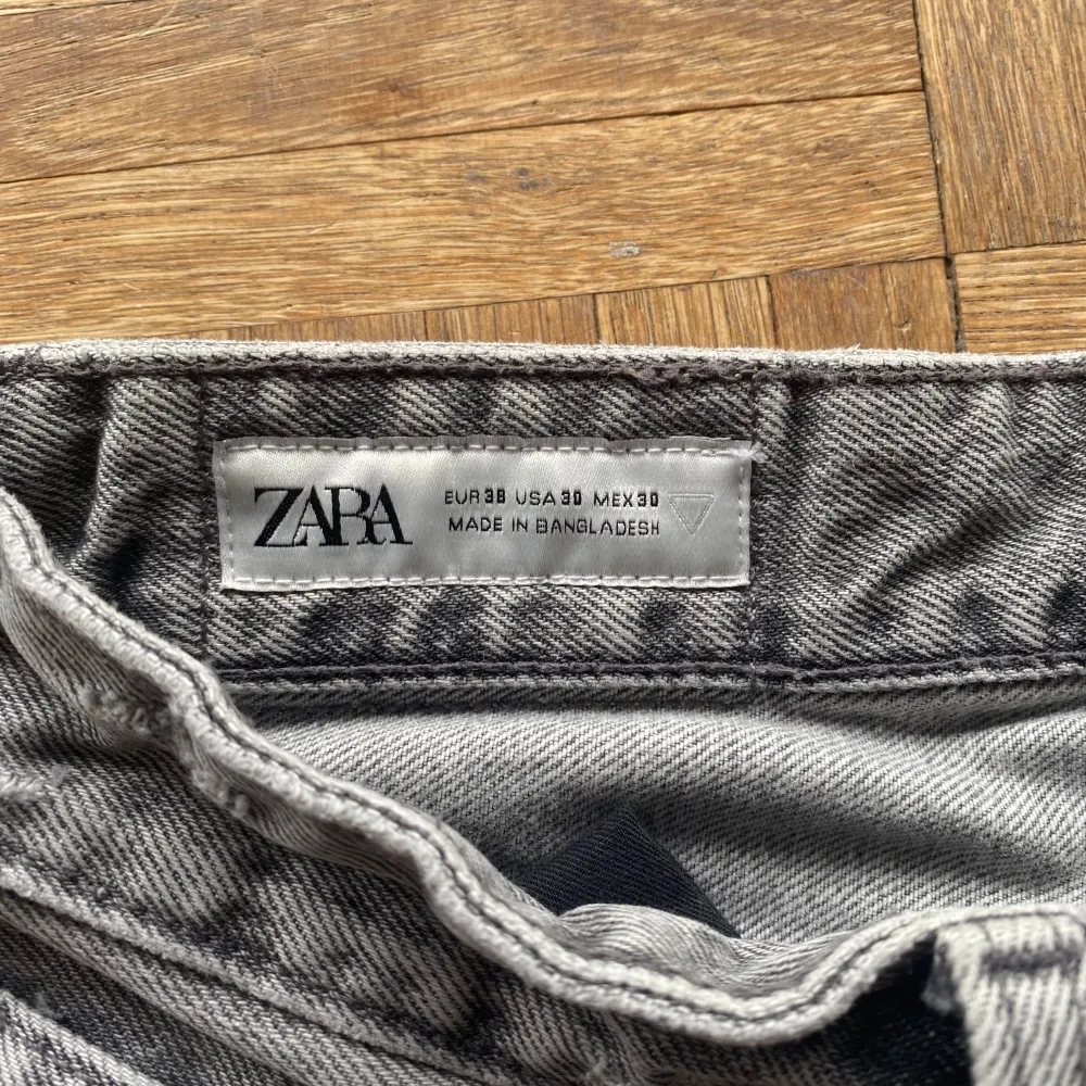 Ett par grå jeansbyxor från Zara i storlek herr 38. Byxorna har en klassisk design med fem fickor och knappgylf. De är tillverkade i ett slitstarkt material och har en rak passform.. Jeans & Byxor.