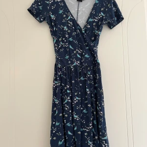 Omlottklänning från ASOS  - Söt omlottklänning från Asos med fåglar och blommor på i mjukt stretchigt material. Sparsamt använd men syns att den blivit tvättad.