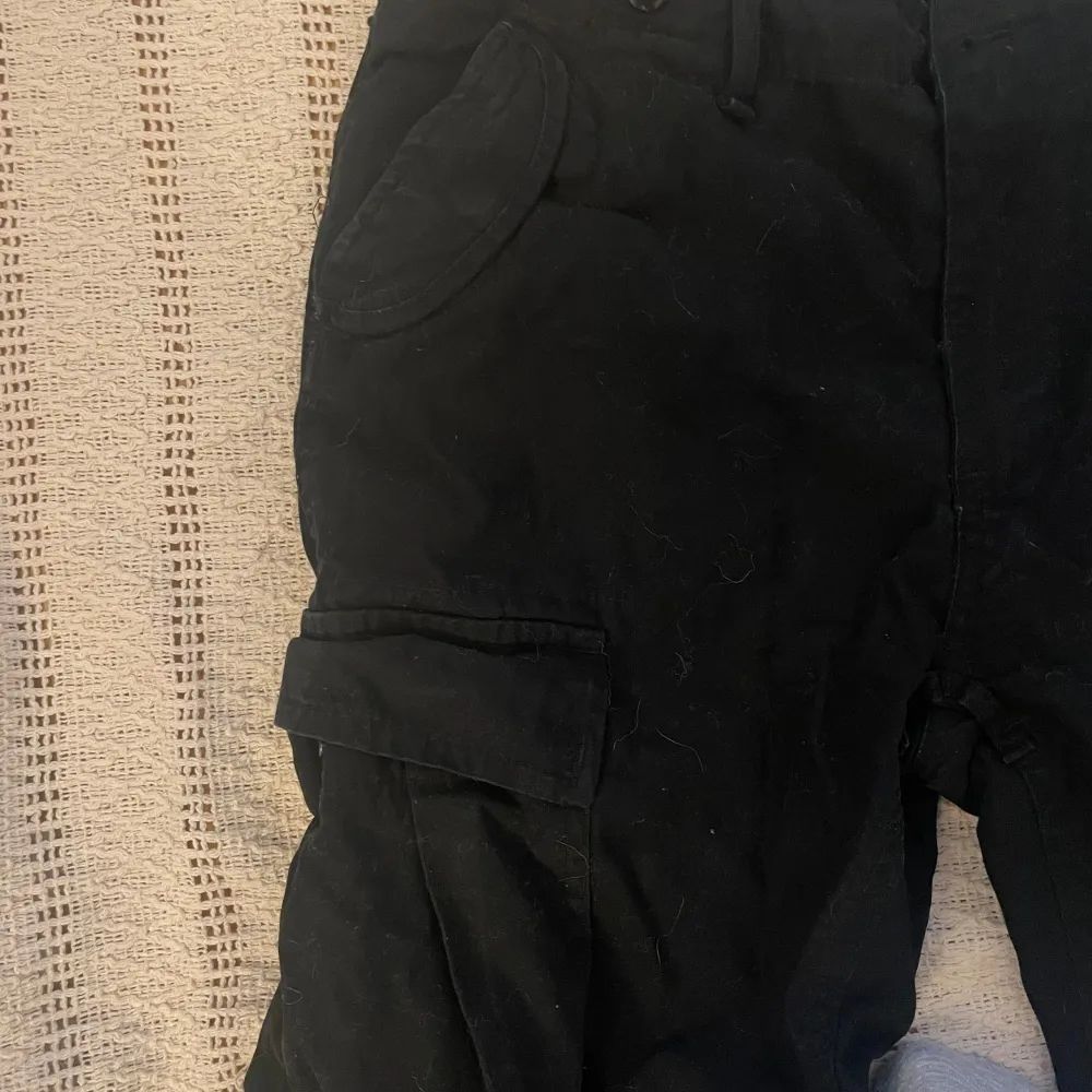 Svarta lågmidjade cargobyxor från Brandit Storlek W30 passar S/36 Finns lite slitage på botten av benen men tycker att det adderar till den tuffa looken. Jeans & Byxor.