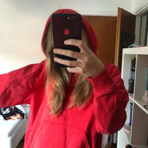 Röd hoodie från Weekday - En röd hoodie från Weekday i storlek XS. Hoodien har en klassisk design med en stor ficka på framsidan och en huva. Den är långärmad och har ribbstickade muddar vid ärmslut och nederkant.