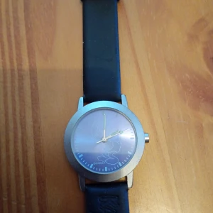 Klocka motiv Kalle Anka 35 mm. - Klocka med urtavla motiv Kalle Anka silverfärgade.35 mm. Rem.