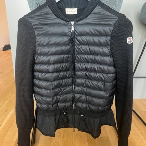 Moncler cardigan dam  - Moncler cardigan dam jacka, just denna modellen har slutat säljas och kommer inte till användning där av säljs den. Köpt för 10 000 kr, sparsamt använd och inga defekter. I storlek XS men passar S med. Lappar finns kvar men inget band så de är lösa. 