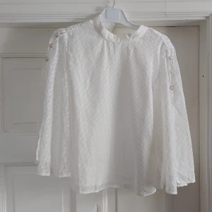 Vit blus - Vit, ganska skir, blus med öppna ärmar pch fina knappar. Stl S/36, men ganska stor i storleken. Helt ny, aldrig använd.