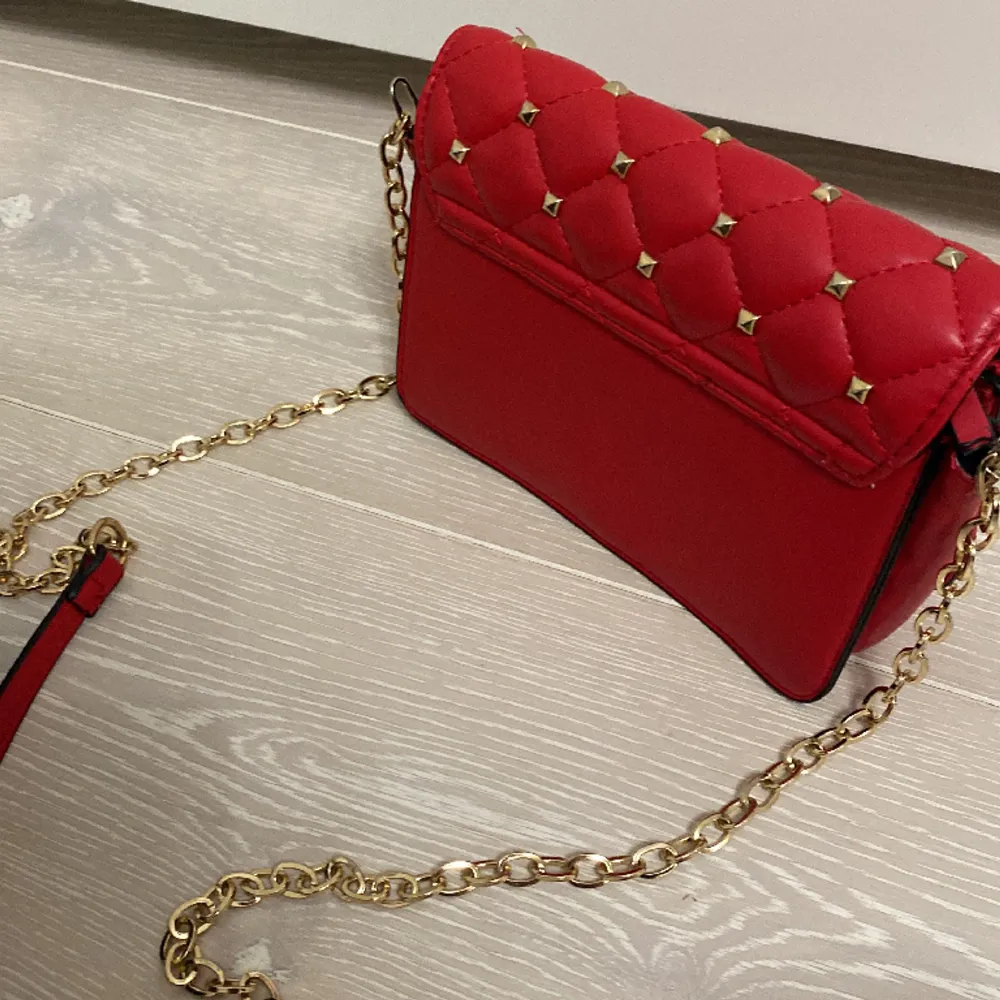 Jättefin röd väska med nitar från Gina Tricot 💗 använd väl och har några sminkgläckar i sig men tror dem skulle gå lätt bort med papper och vatten 💗 skriv för fler bilder eller frågor. Väskor.