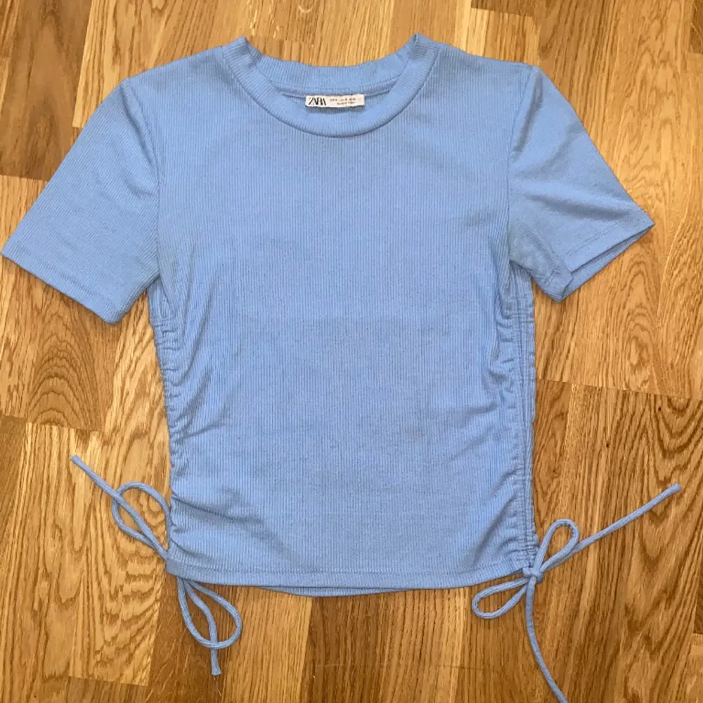 Blå kortärmad tröja med justerbara band på sidorna. Från Zara. Använd ca 2 gånger och är i mycket bra skick. Kontakta för fler bilder. Priset kan diskuteras!. Toppar.