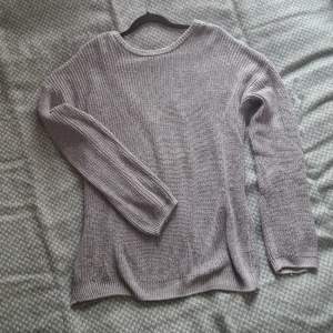 En ljusgrå stickad tröja med öppen rygg. Oversized-fit. Små noppror på framsidan längst ner (synliga på första bilden).