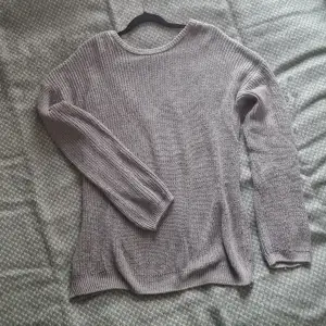 En ljusgrå stickad tröja med öppen rygg. Oversized-fit. Små noppror på framsidan längst ner (synliga på första bilden).
