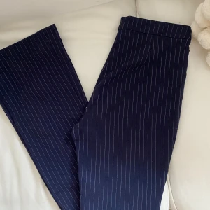 Randiga kostymbyxor - Blårandiga kostymbyxor som tyvärr är för små. Skulle säga att de är raka med en liten bootcut. En liten defekt i att dragkedjan inte går ända upp men annars superfina!