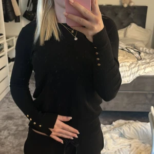 Svart tröja med guldknappar på sidan  - Jättefin svart tröja med guldknappar ifrån zara som inte längre säljs. Använd fåtal gånger så den är i nyskick