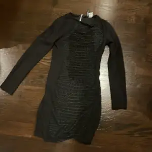 Denna svarta klänningen är väldigt lång. Midjan: 30cm, längden: 70cm. Den har en dragkedja som man drar upp på baksidan. Har även lite detaljer på. Men jättefin och använd 1 gång, köp!💘