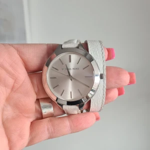 Klocka Michael Kors - Superfin klocka, Michael Kors med vitt läderarmband. Fungerar som dem ska, men behövs ett batyeribyte. Modell på klockan: MK-2325