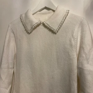 Stickad klänning - Säljer denna vita klänningen med pärlor på. Använd 1 gång🤍