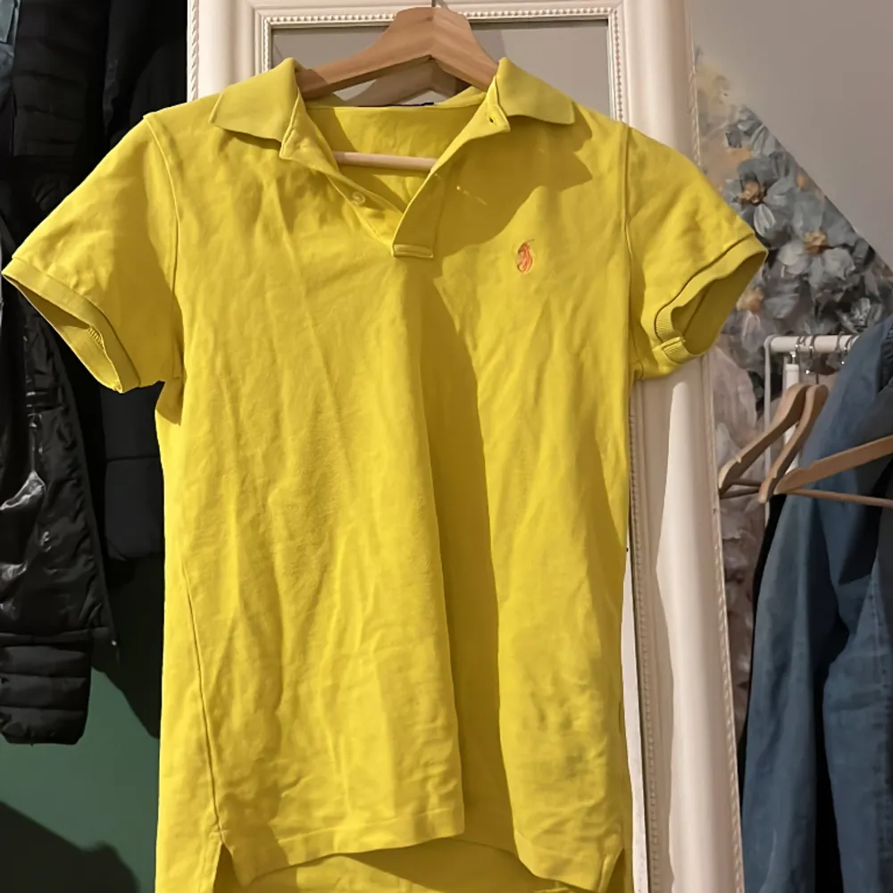 Snygg gul polo T-shirt från Ralph Lauren. Praktiskt taget oanvänd. Storlek M men passar också S. Relativt lång.. Toppar.