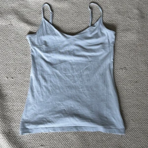 Ljusblå linnetopp från 157 - Säljer en ljusblå linnetopp från 157 i storlek XS. Toppen är tillverkad av 95% bomull och 5% elastan, vilket gör den både bekväm och stretchig. Perfekt för sommaren eller som ett basplagg i garderoben. Den har smala axelband och en enkel design som passar till det mesta. 🩵