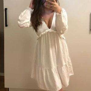 Vit klänning - Vit långärmad klänning med volanger lite öppen ryg