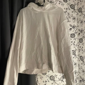 Vit hoodie - Säljer en vit hoodie som är supermysig och perfekt för kalla dagar. Den har en luva med snörning och är långärmad. Passformen är lite oversized vilket gör den extra bekväm. Perfekt för höst och vinter!