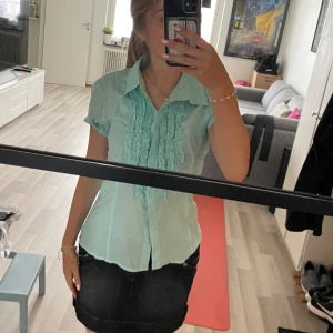 Blus - Kortärmad turkos blus med lite volang  Storlek:M