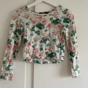 Säljer en superfin blommig topp från BikBok i storlek S. Den är vit med rosa och gröna blommor över hela tyget. Toppen är långärmad och croppad, perfekt för vår och sommar. Materialet känns som bomull och är väldigt bekvämt. Passar både till vardags och fest!