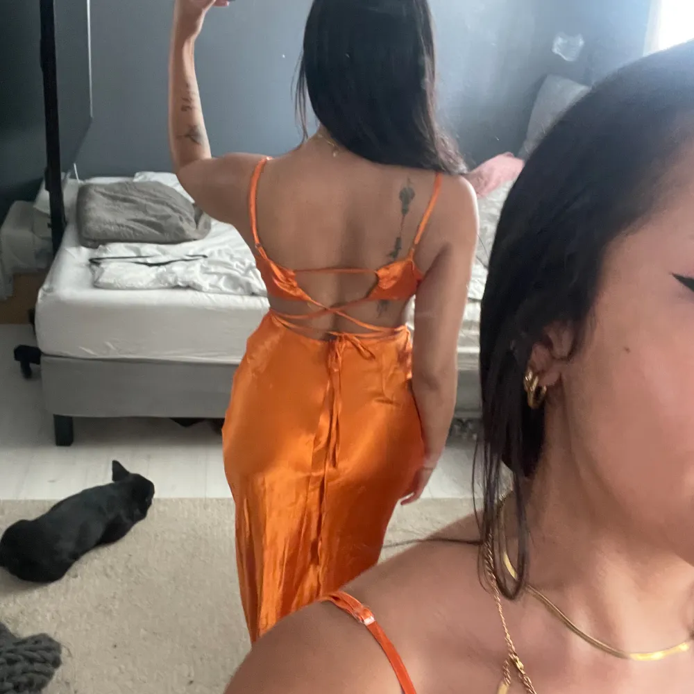 Orange midi klänning med cut out på sidorna. Siden material. Sömmen har gått upp lite vid midjan, se sista bilden och lite defekt i tyget på flera ställen. Klänningar.