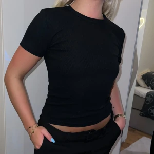 Svart ribbad t-shirt från Zara - Säljer en svart ribbad t-shirt från Zara i storlek S. Den är kortärmad och har en tight passform som framhäver figuren. Perfekt för både vardag och fest! 🖤