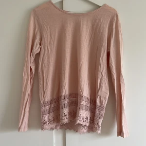 Rosa långärmad tröja från Ellos - Säljer en superfin rosa långärmad tröja från Ellos i storlek 38/40 (M). Tröjan är gjord av mjukt material och har vackra spetsdetaljer längst ner. Perfekt för både vardag och fest! 💖