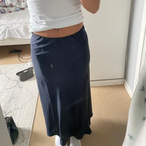 Mörkblå långkjol från Gina Tricot - Säljer en snygg mörkblå långkjol från Gina Tricot i storlek XS. Kjolen är i ett mjukt och bekvämt material, perfekt för både vardag och fest. Den har en enkel och stilren design som gör den lätt att matcha med olika toppar. Passar perfekt för höst och vår! Aldrig använd och är i silke!