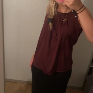Vinröd ärmlös topp - Säljer en snygg vinröd ärmlös topp. Den är perfekt för både vardag och fest. Toppen är i ett mjukt och bekvämt material, vilket gör den skön att ha på sig hela dagen. Den har en lös passform och är lätt att matcha med olika outfits. Perfekt för höst och vår!