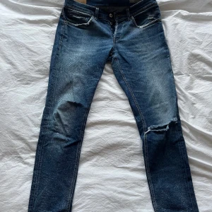 Dondup George  - Dondup George i storlek 34  Byxorna är i ”sliten” utformning med slitna ändar. Jeansen har ett hål på vänstra knät. Jeansen är i fint skick. Passar mig som är 185.  Om ”vanliga” ändrar önskas kan man enkelt du upp det hos en skräddare för ca 50 kr