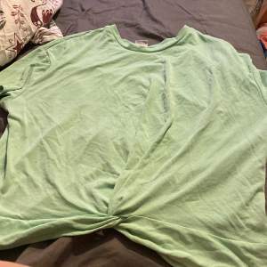 En fin ljusgrön/Limegrön t-Shirt med en liten knyt framtill, Tröjan är inte kroppad. Skönt material