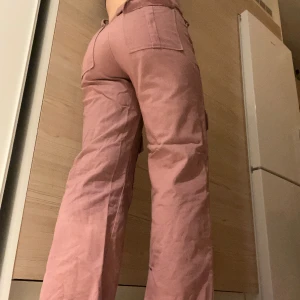 Rosa byxor - Rosa tygbyxor i storlek 34. Älskar färgen men växt ur dem! Haken man använder för att knäppa gylfen har gått sönder. Frakt ingår inte i priset! <3
