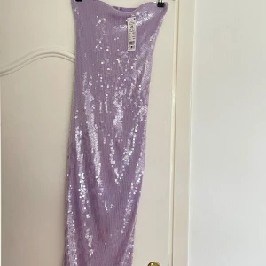 Glitter klänning - Säljer denna helt oanvända klänningen från Gina. Sitter otroligt fint och har en slitts baktill. Säljs på grund av att den inte kommer till använd. Nypris 599kr