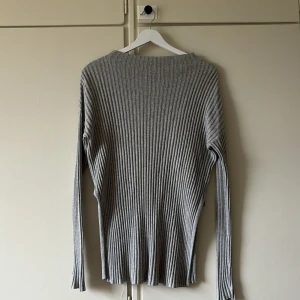 Stickad tröja - Grå stickad tröja från Åhléns. Superfint ribbat material, har en fin slits på sidan som gör den lite speciell och skön att ha på sig ✨