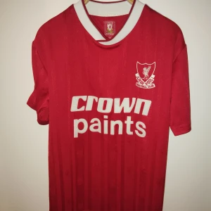 Liverpool fotbollströja - Liverpooltröja med vintage design, inköpt på Anfield i LFCs officiella affär. Knappt använd och i utmärkt skick 